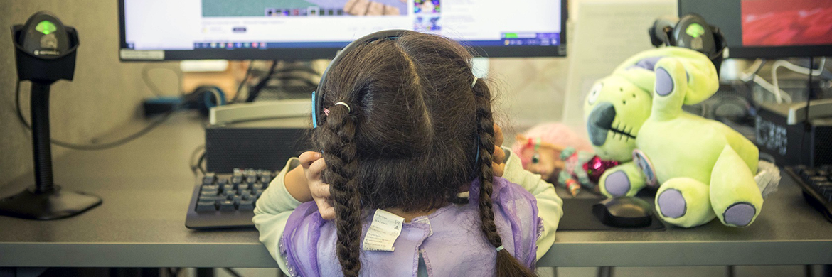 Young girl sitting at a desktop computer in the library