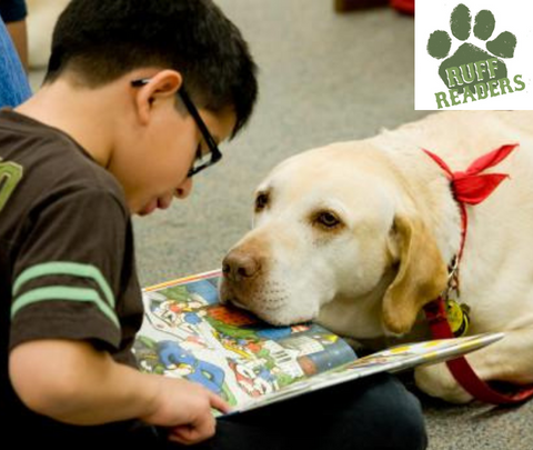 image of a boy reading a book to a dog looking on