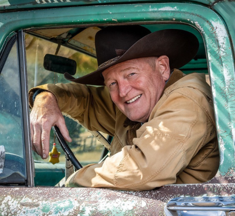 image of Craig Johnson wearing a cowboy hat and sitting in an old pickup truck