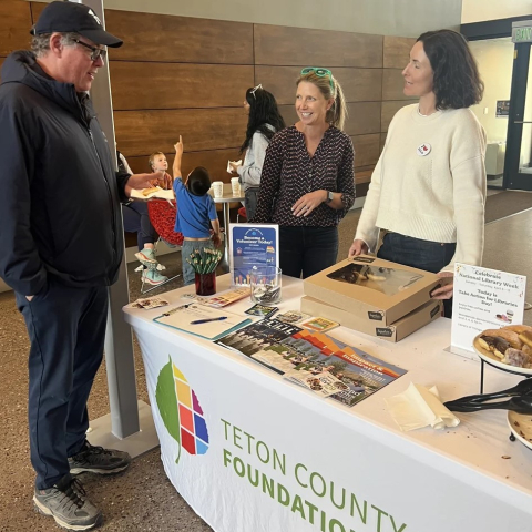 image of three people talking near a table with donuts