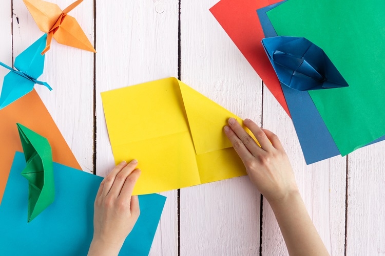 image of hands folding squares of colorful paper