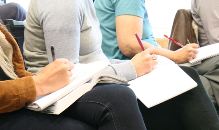 image of several people writing with pens on paper